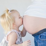 Little Girl Kissing New Sibling to Be